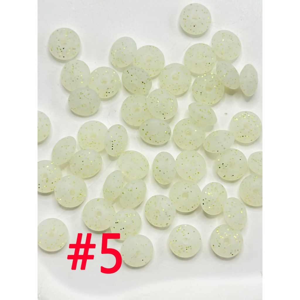 A collection of round silicone beads in various colors including white, pink, blue, and green, displayed on a flat surface.

