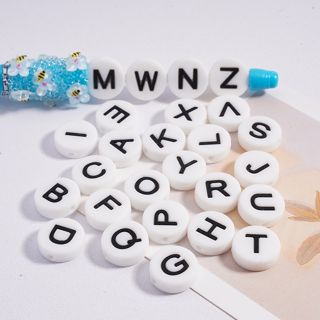 White letter beads with black letters on a light surface

