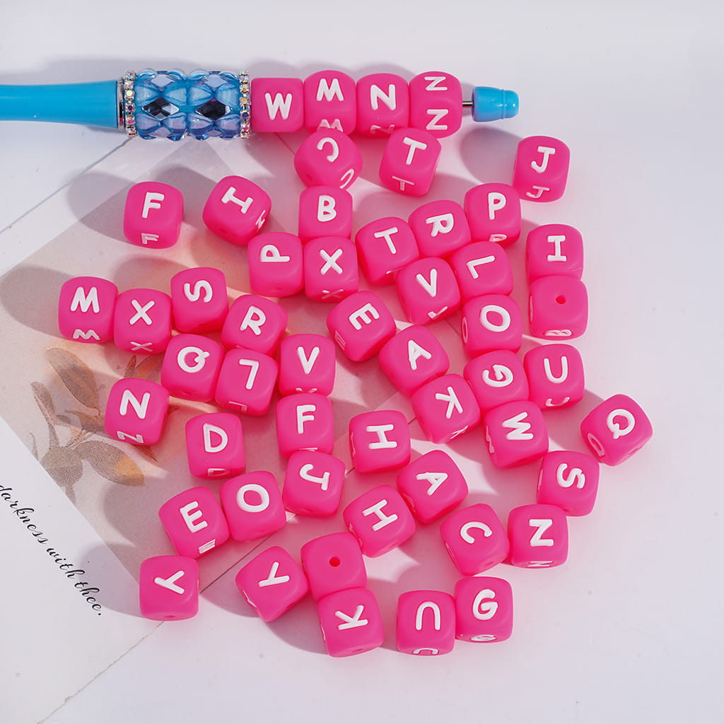 Pink letter beads with a blue tool on a white background