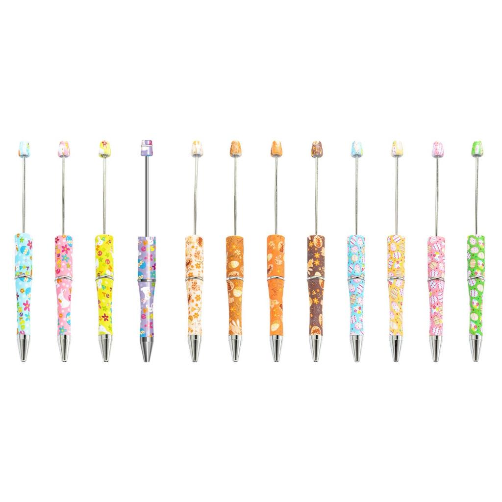 A collection of printed beadable pens with multicolored patterns, arranged in a row.

