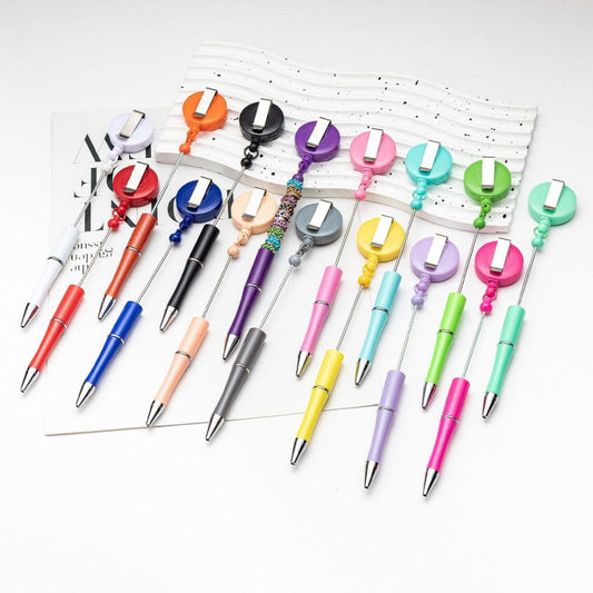 A collection of colorful beadable plastic pens with spinning back badge reels displayed on a surface.

