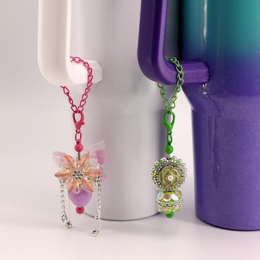 A lobster clasp in solid colors attached to a chain, designed to be used as a pendant holder for cups and tumblers, displayed against a white and purple background.

