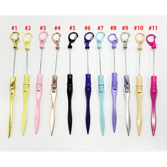 A range of colorful metal letter openers with bead embellishments on the handles displayed in a line.

