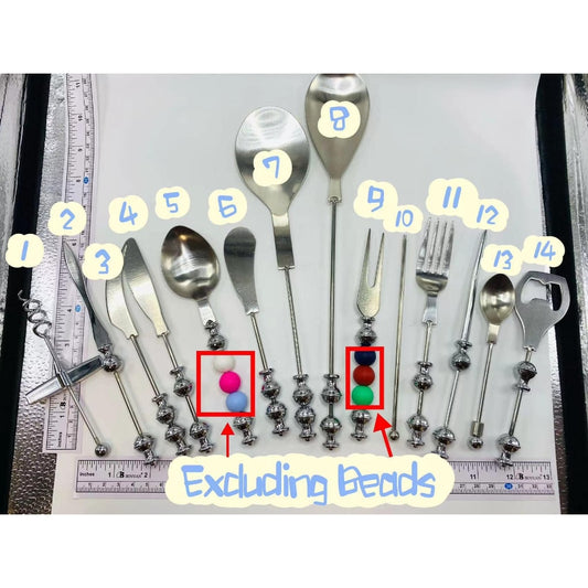A collection of stainless steel flatware and barware tools, including an envelope opener, corkscrew, cheese butter knife, dessert spoon, fork, teaspoon, and grill utensils, with decorative beads attached to some of the tools.

