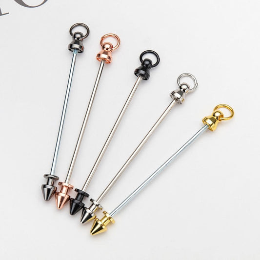 A selection of metal keychains with beadable bars in various colors including silver, rose gold, black, gold, and gunmetal.


