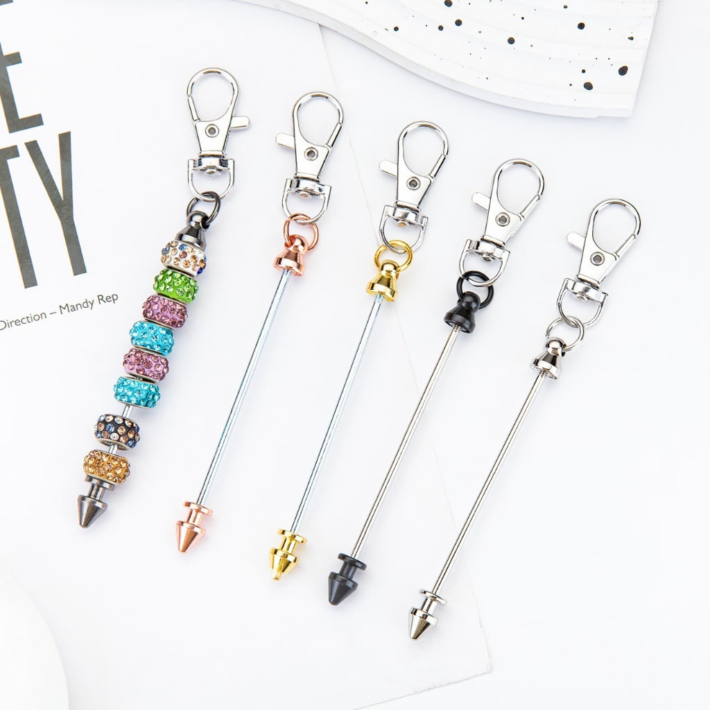 A selection of metal bullet head keychains with beadable bars and lobster clasp hooks in various colors.

