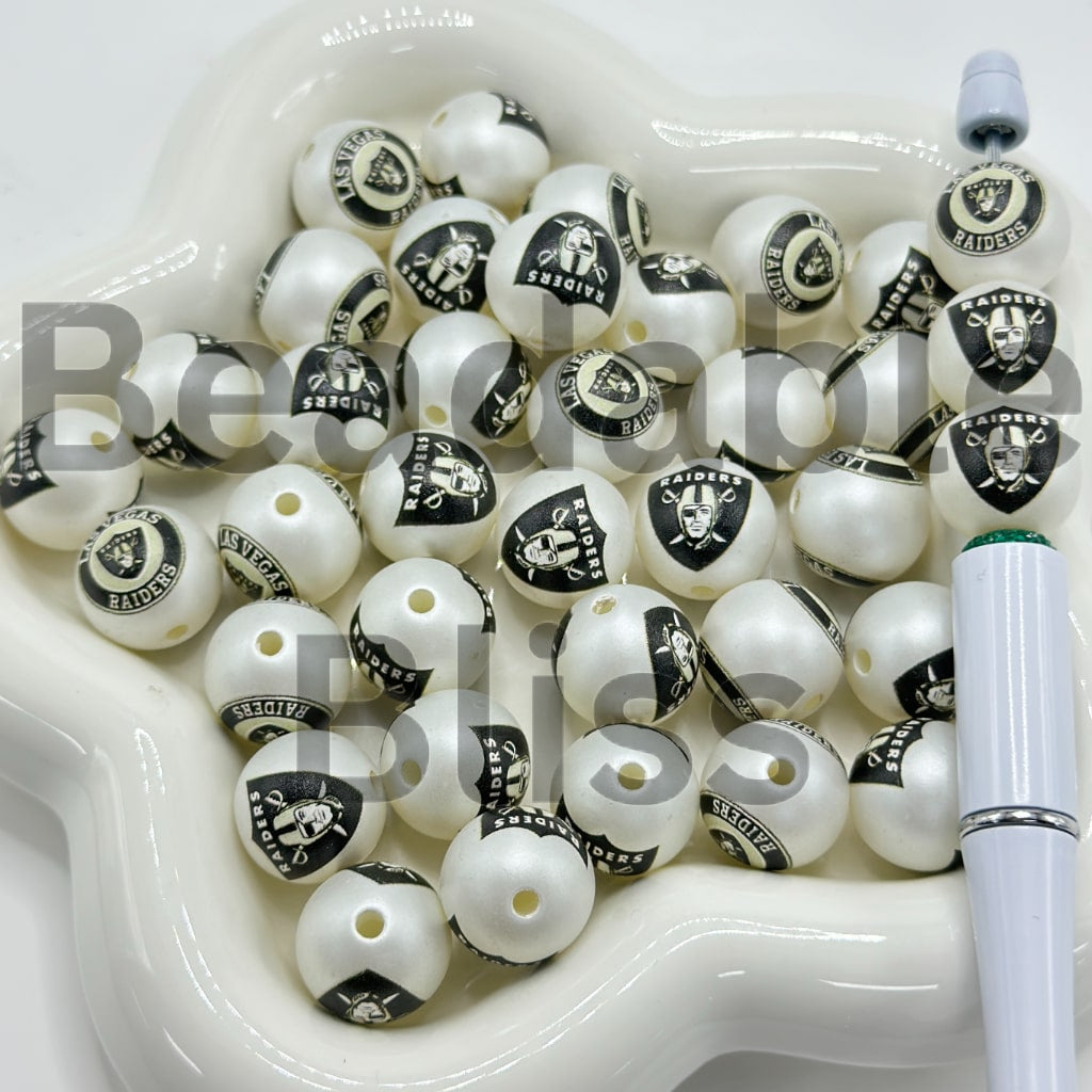 White and black beads with Raiders logo in a white container

