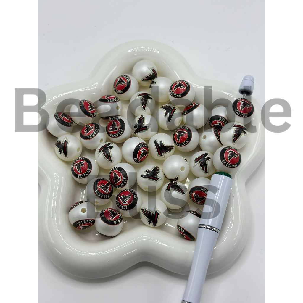 White beads with logos on a white dish with a pen

