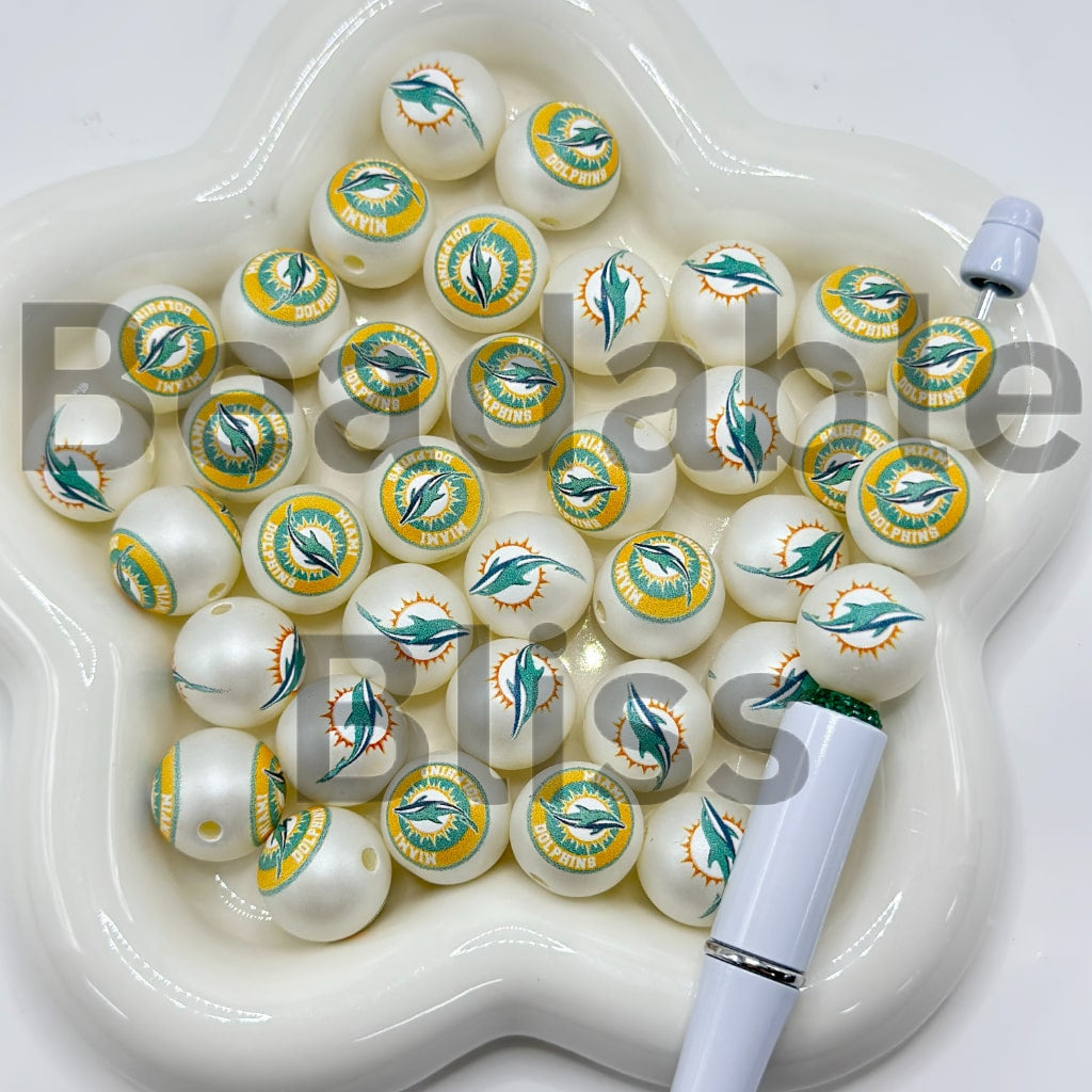White beads with sports team logo in a white dish with a white tool

