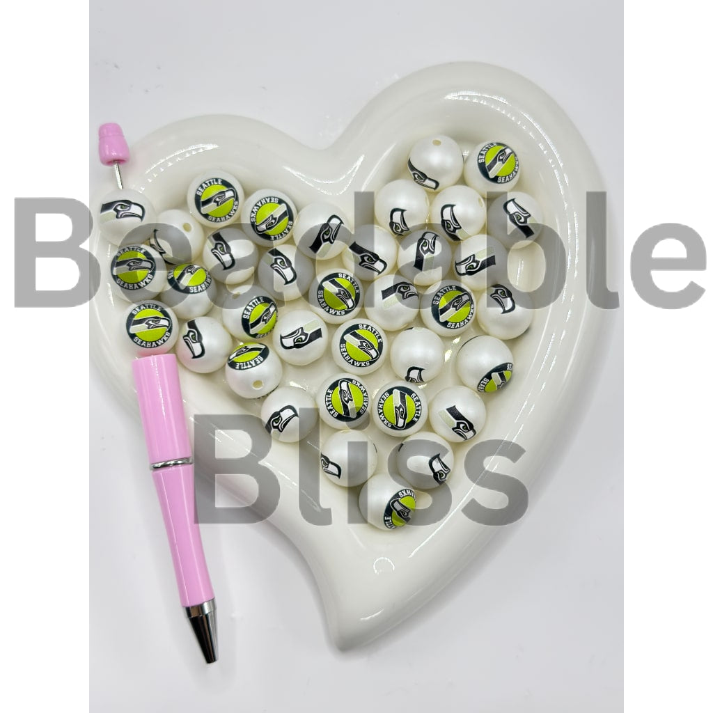 Heart-shaped dish with white beads featuring symbols and a pink pen on a white background

