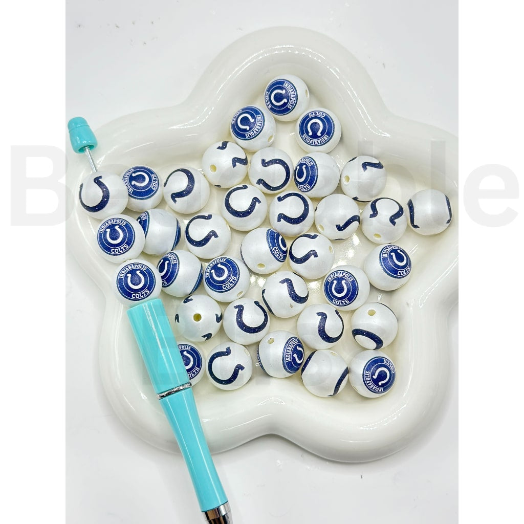 White beads with blue and black designs and a blue pen on a white heart-shaped stand.

