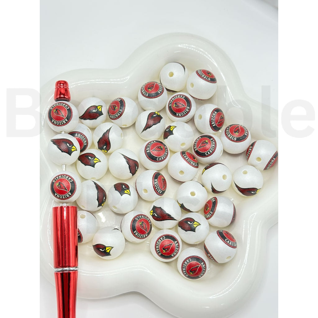 Set of white beads with red and black designs on a heart-shaped tray with a red pen.

