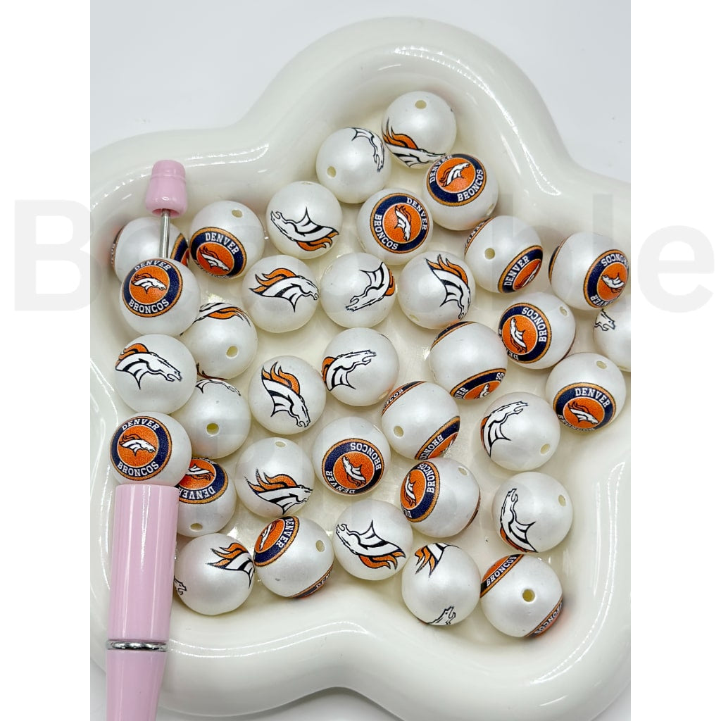 White beads with Denver Broncos logos on a white heart-shaped tray

