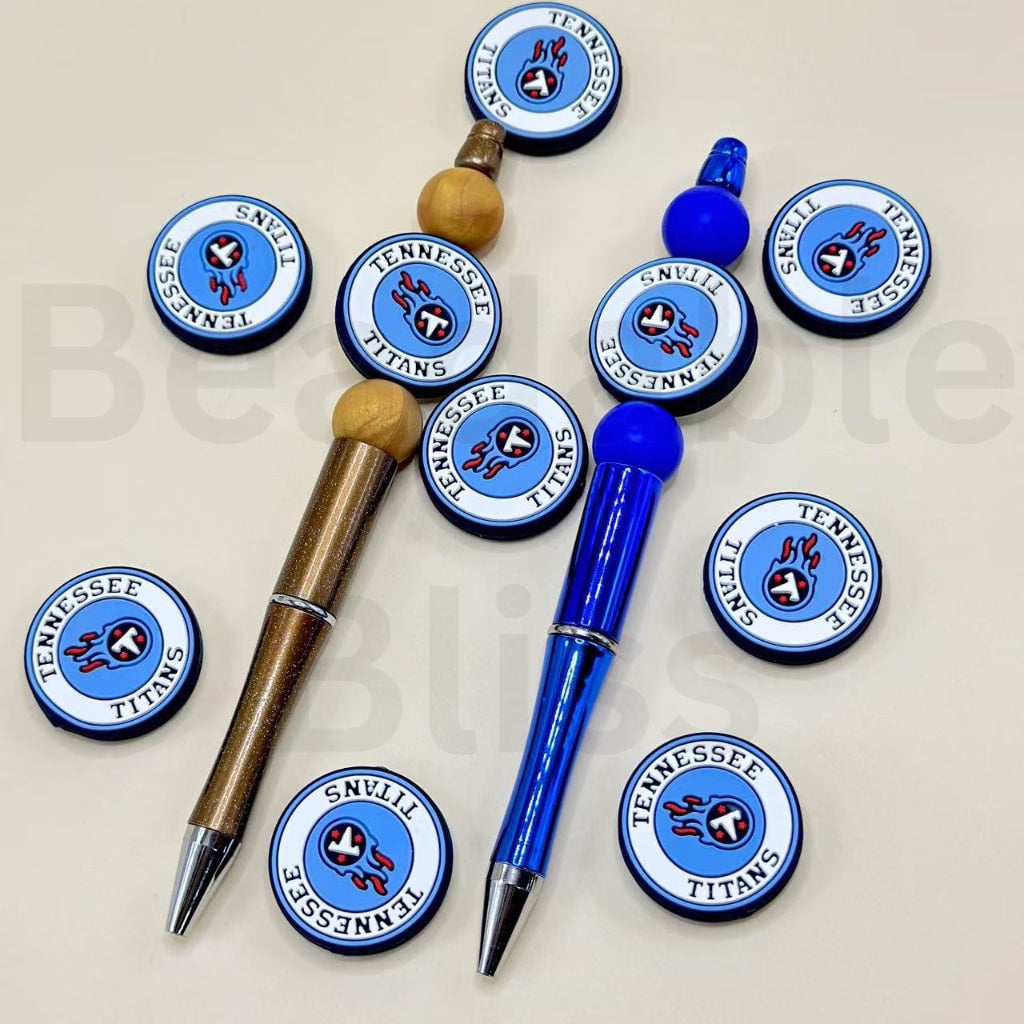 Two pens, one blue and one brown, with Tennessee Titans logo buttons on a light gray background.

