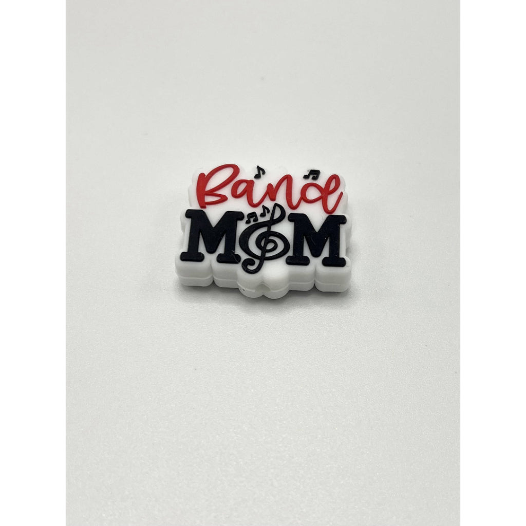 A silicone bead with the text 'Band Mom' and musical notes on it, primarily in black and red colors.


