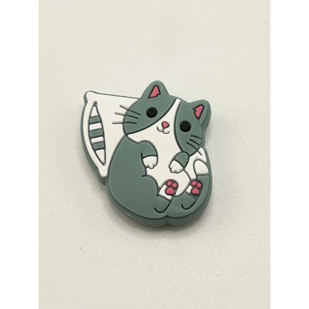 A silicone bead in the shape of a cartoon cute cat on a pillow.

