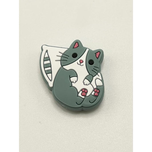A silicone bead in the shape of a cartoon cute cat on a pillow.


