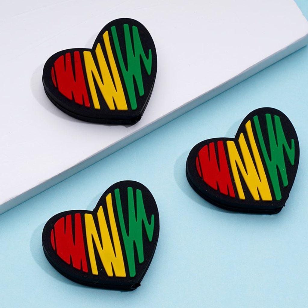 Silicone beads in the shape of hearts with a multicolored design representing the African flag.

