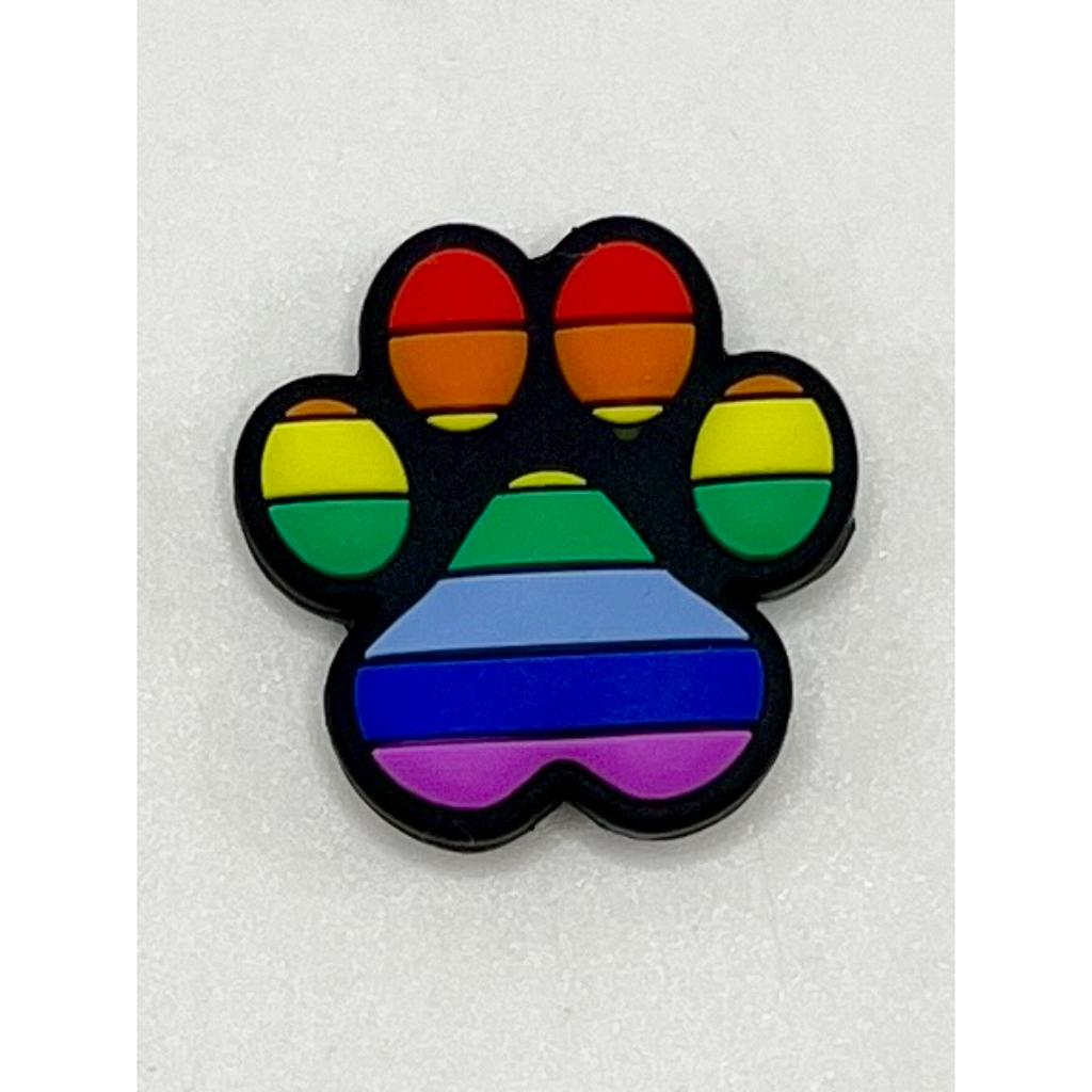 A silicone bead in the shape of a paw print with a multicolored rainbow pattern.

