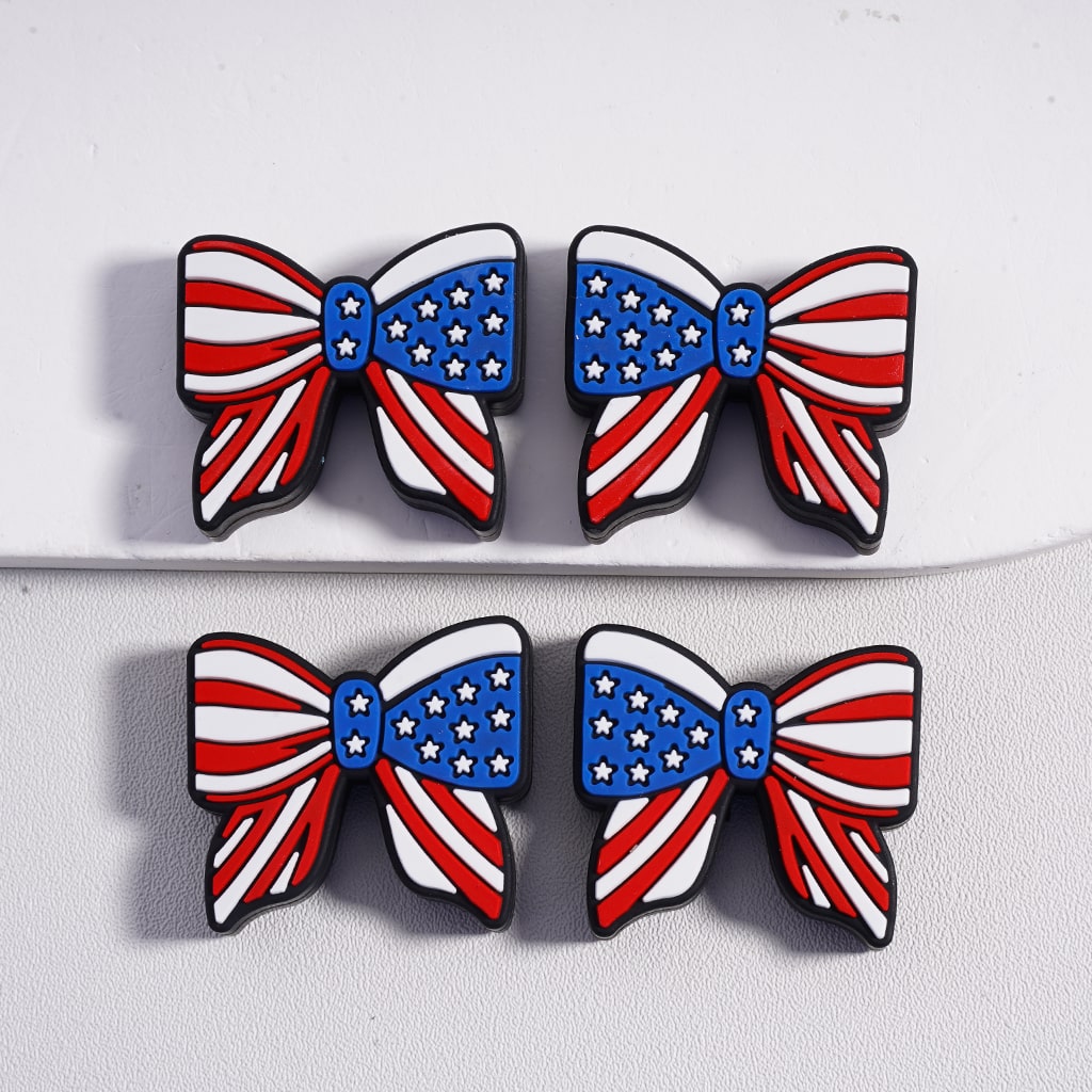 Four American flag-themed bow-shaped pins on a white background

