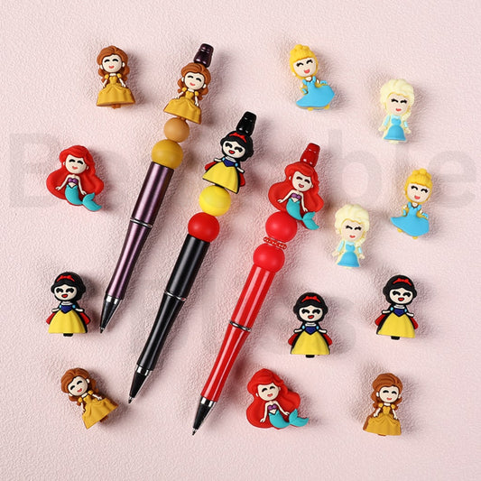 Three pens with colorful princess figurine toppers on a light pink background, with 'beadablebliss.com' branding.

