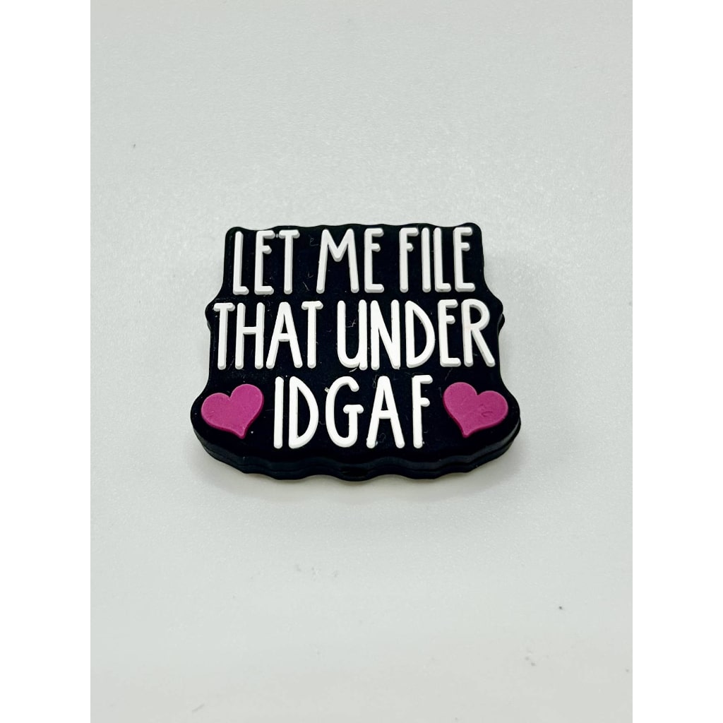 A black silicone focal bead with white text and pink accents that reads 'LET ME FILE THAT UNDER IDGAF'.

