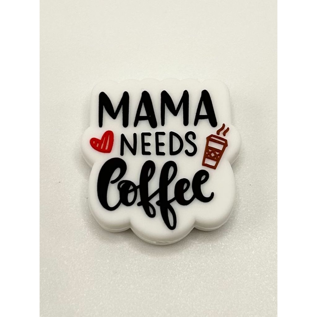 A silicone bead with the text 'MAMA NEEDS COFFEE' printed on it, primarily in black color with additional red and white details.

