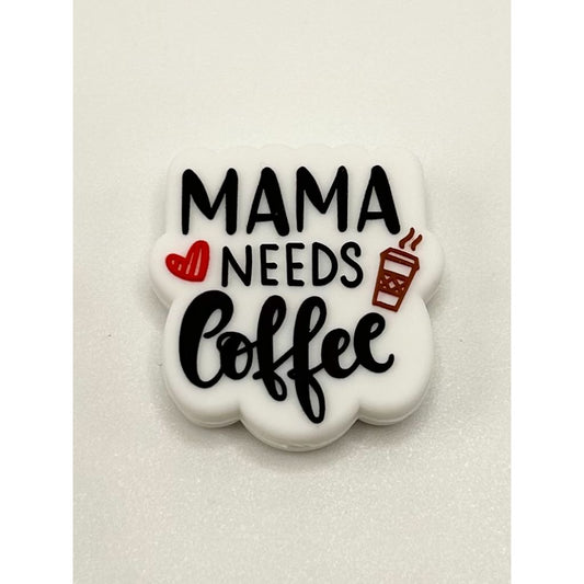 A silicone bead with the text 'MAMA NEEDS COFFEE' printed on it, primarily in black color with additional red and white details.

