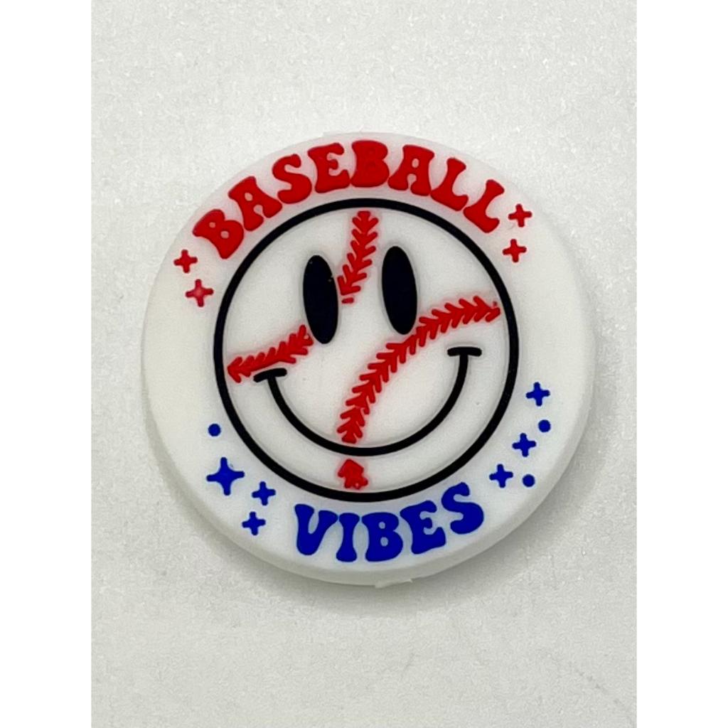 A silicone bead with a smiley face design, featuring the text 'BASEBALL VIBES' and decorative elements such as stars and a baseball pattern in red and white colors.

