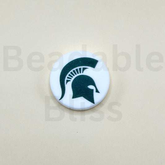 Round white sticker with green Spartan helmet logo on a beige background

