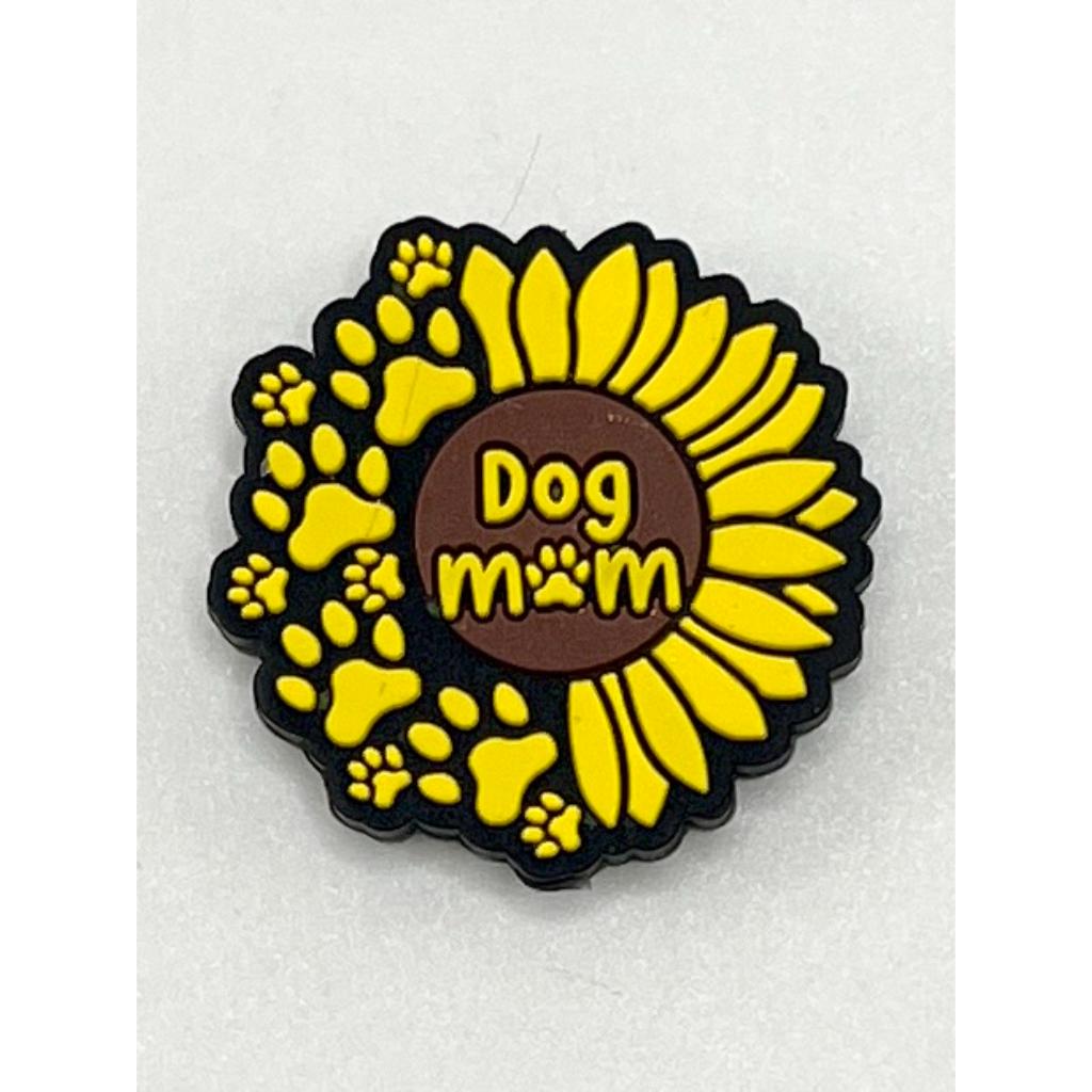 A silicone bead with a design resembling a sunflower, in yellow and brown colors, with the text 'Dog Mom' in the center.

