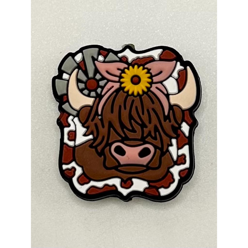 A silicone bead featuring a brown cow with a sunflower design on its head.

