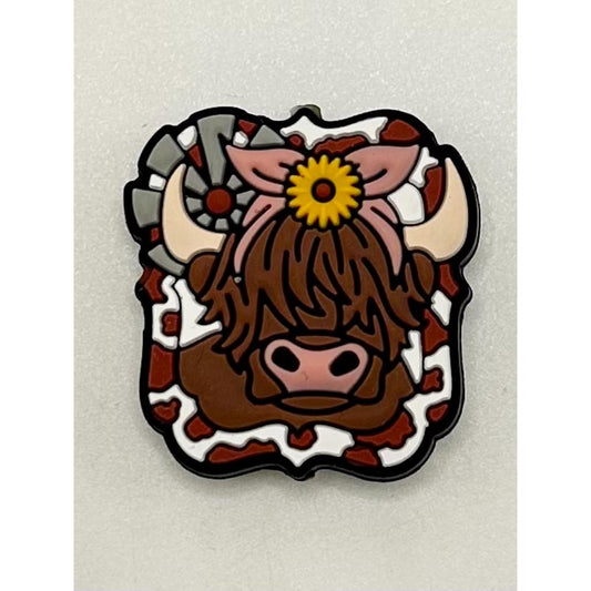 A silicone bead featuring a brown cow with a sunflower design on its head.

