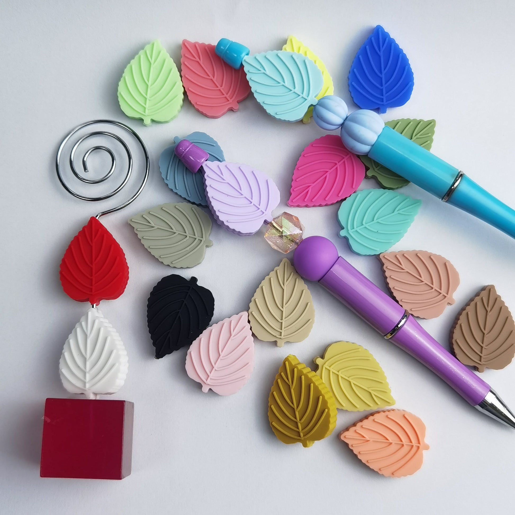 Colorful leaf-shaped erasers on a white background with two pens.


