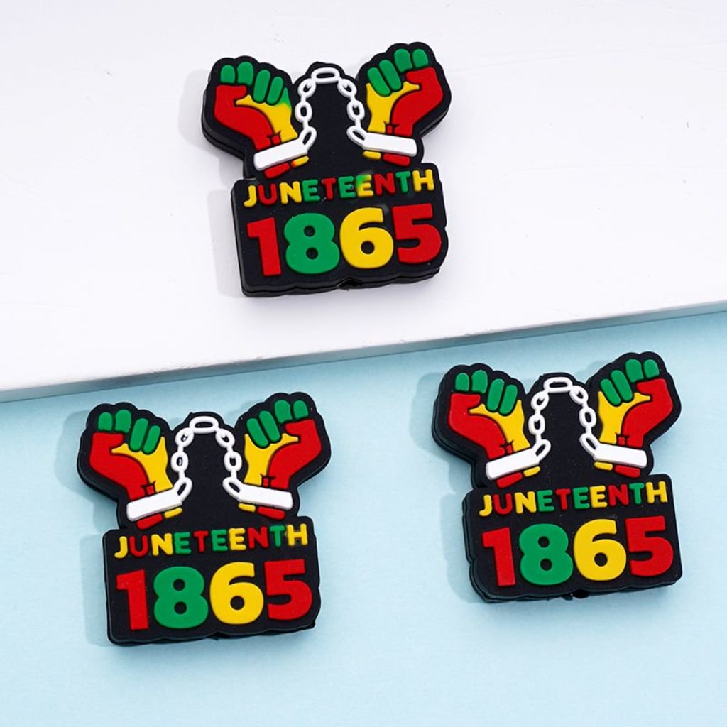 A set of silicone beads with the text 'JUNETEENTH 1865' and colorful fist designs, likely used for crafting jewelry.

