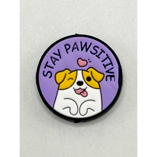A silicone focal bead featuring a cartoon dog with the phrase 'STAY PAWSITIVE' written around it.

