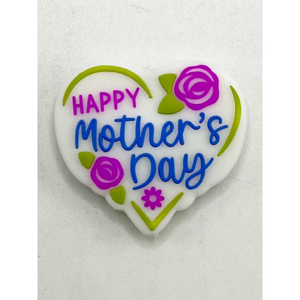 A silicone bead in the shape of a heart with 'Happy Mother's Day' text and floral designs in purple, green, and pink colors.

