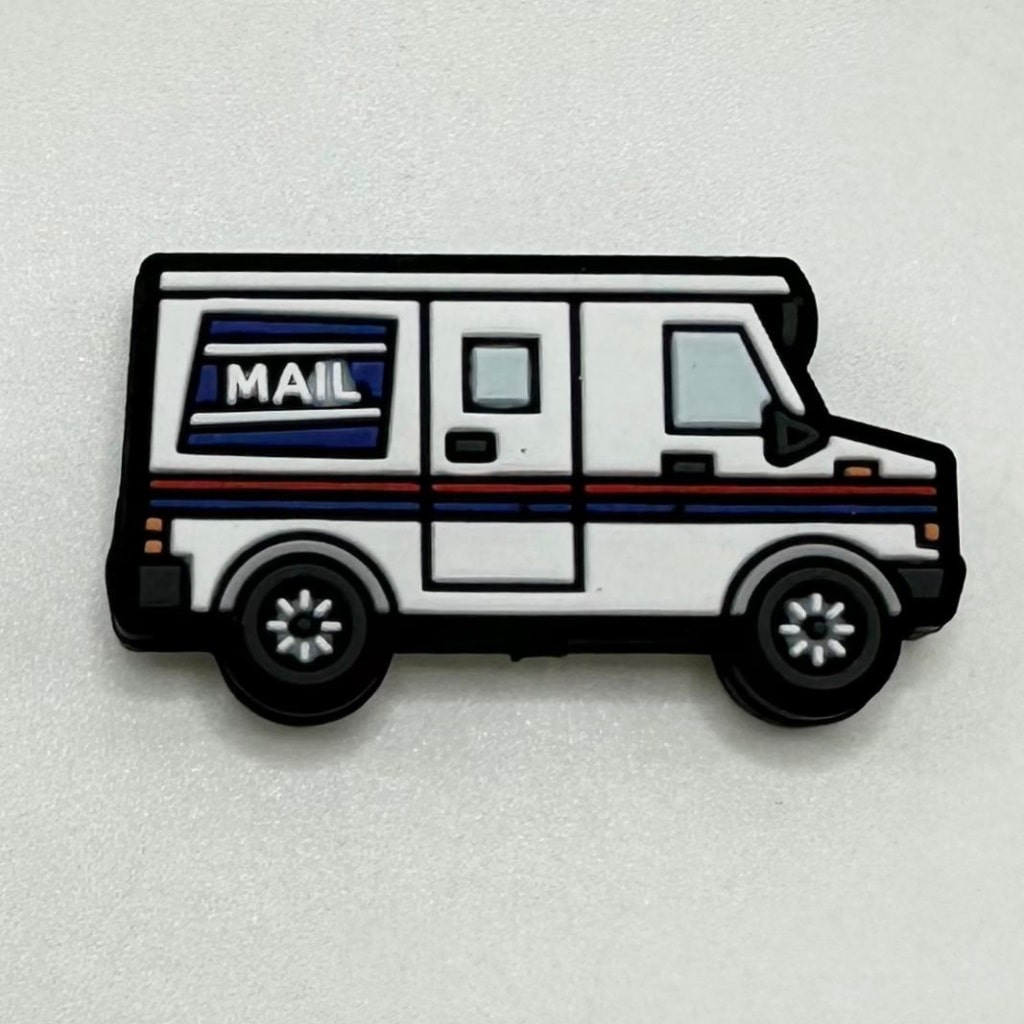 A silicone bead in the shape of a white delivery mail truck with blue and red accents and the word 'MAIL' on the side.

