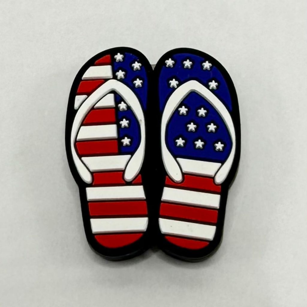 A pair of silicone flip flop shaped beads with a patriotic red, white, and blue design and star patterns.


