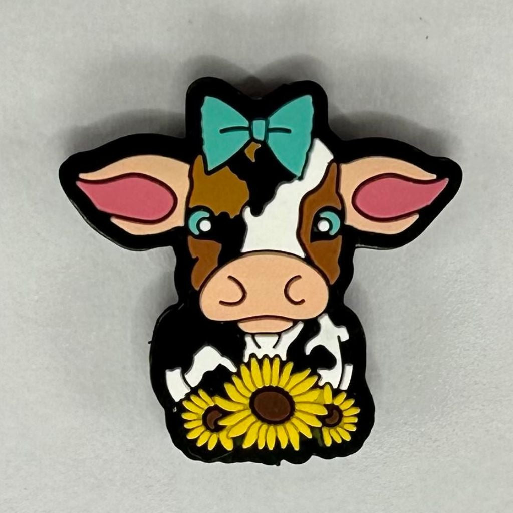 A silicone bead featuring a cartoon depiction of a cow with a sunflower and a bow.

