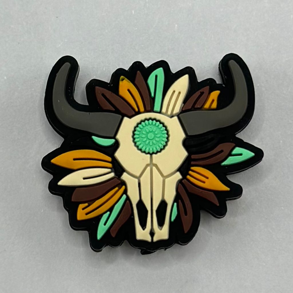 A silicone bead featuring a buffalo skull with a flower aztec print pattern, predominantly in black, brown, and beige colors.

