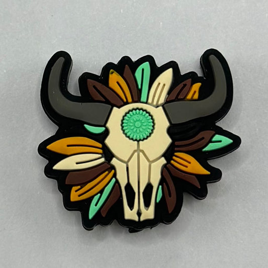 A silicone bead featuring a buffalo skull with a flower aztec print pattern, predominantly in black, brown, and beige colors.

