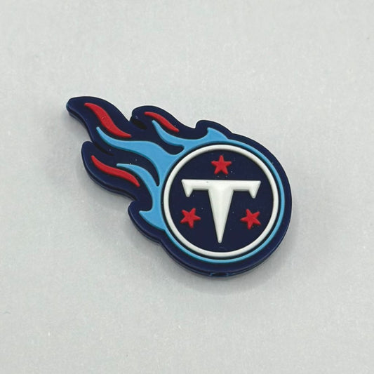 A silicone bead with a design resembling a football team logo, featuring a blue flame, white letter 'T', and red stars.

