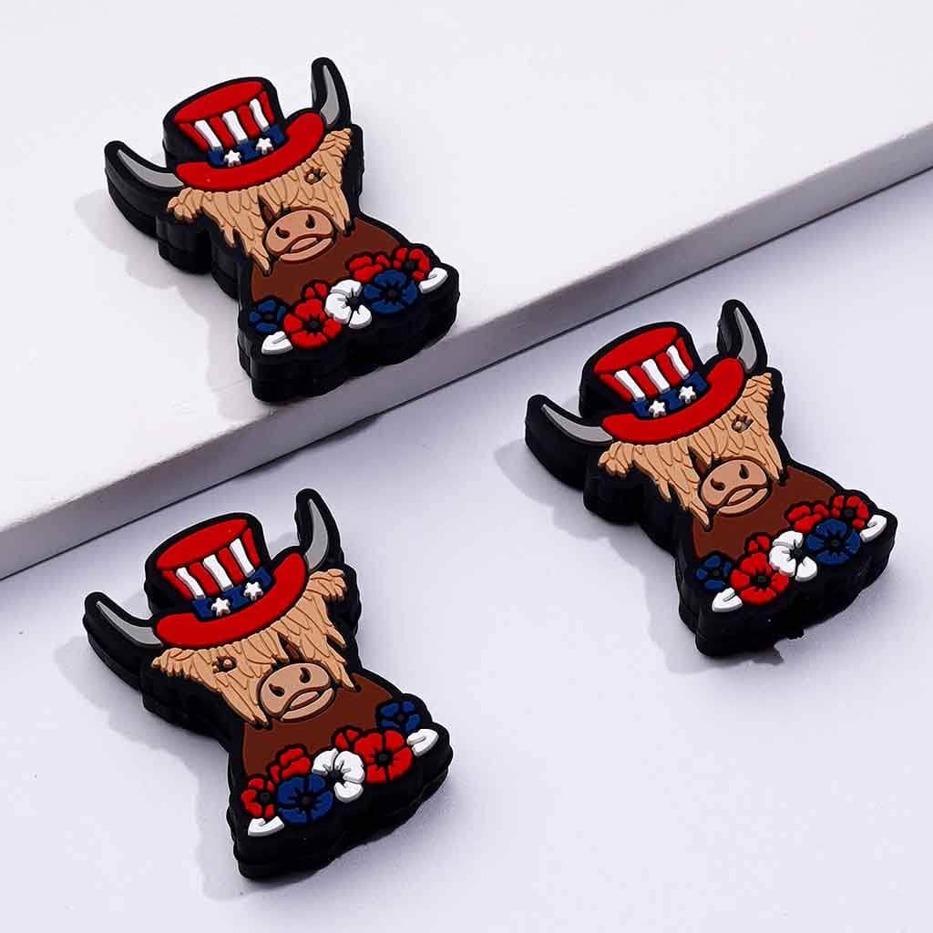 A set of silicone beads in the shape of a cow wearing a USA flag hat with a floral design.

