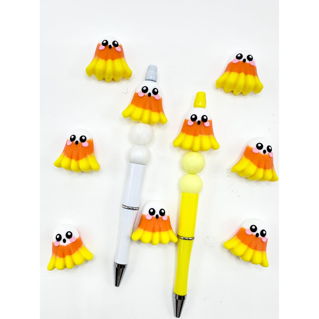 Silicone beads shaped like ghosts in yellow, orange, and white tricolor with eyes, attached to pens.

