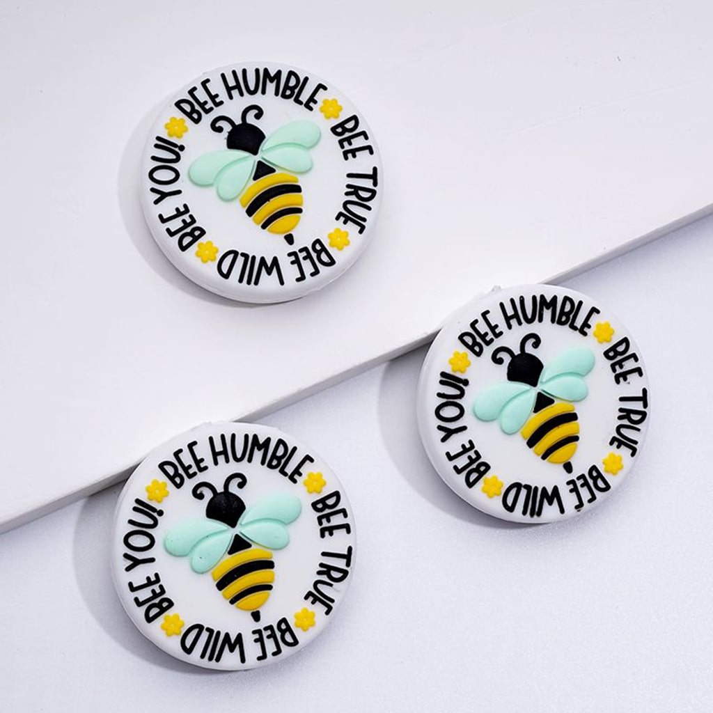 Three round silicone beads with a bee design and the text 'BEE HUMBLE, BEE TRUE, BEE WILD, BEE YOU' printed on them.

