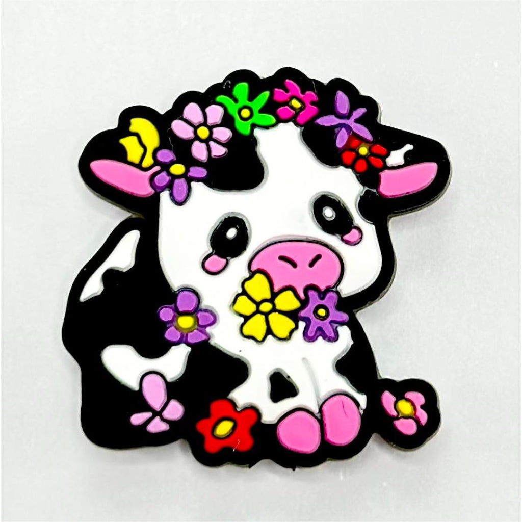 A silicone bead featuring a black and white cow with various colored small flowers.

