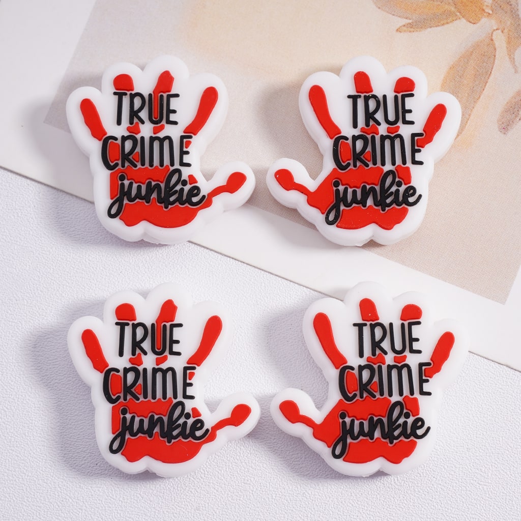 Four 'True Crime Junkie' hand-shaped pins on a light background

