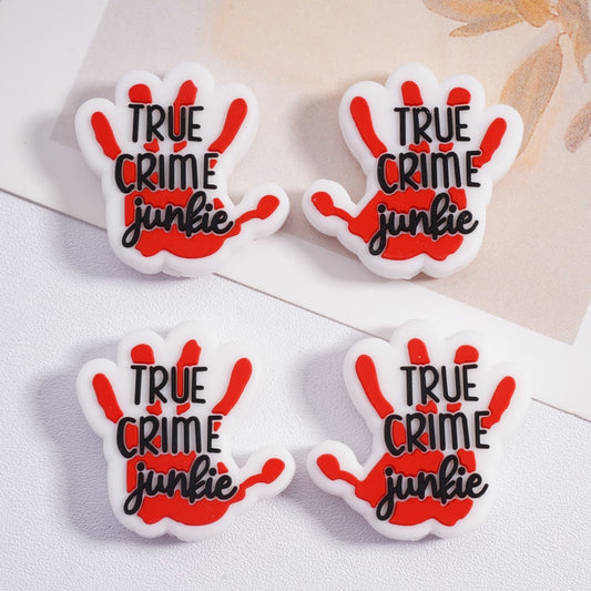 Four 'True Crime Junkie' hand-shaped pins on a light background

