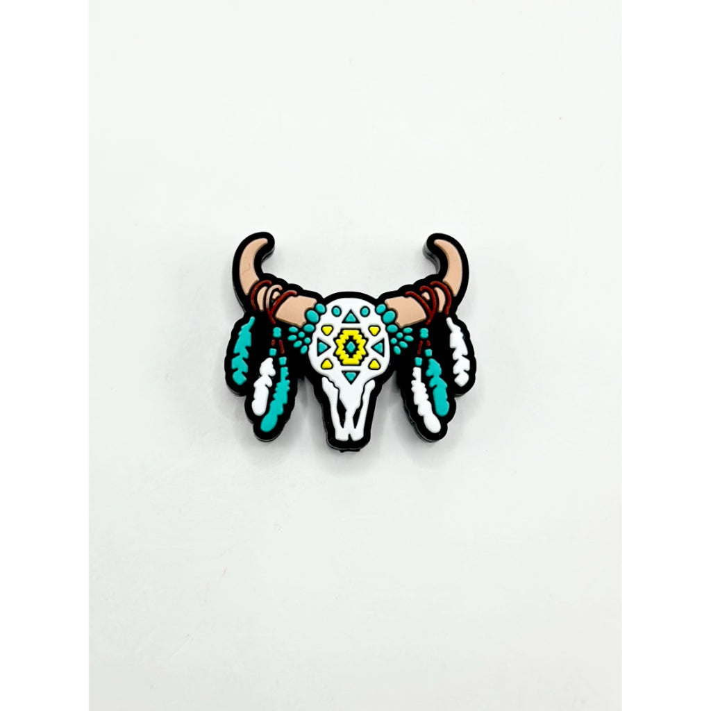 Decorative bull skull with teal feathers and yellow center on a white background

